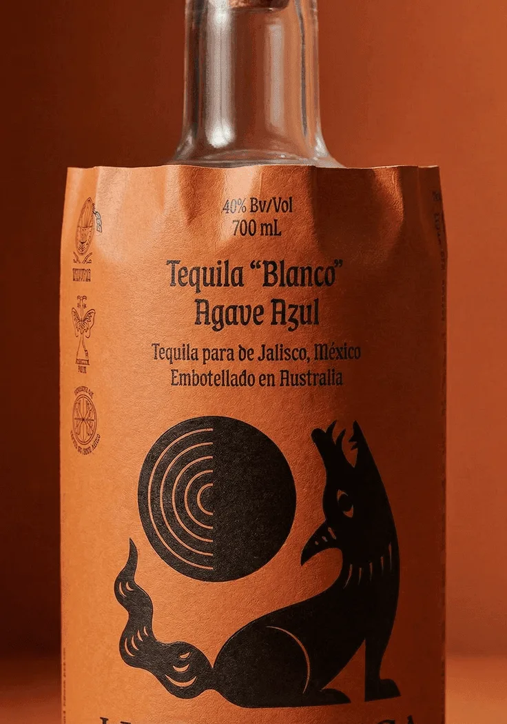 Tequila bottle with an illustrated label on terracotta (Luna Hueca)